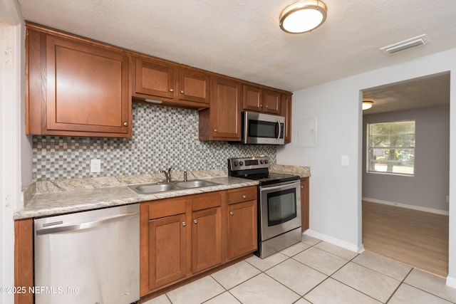 3303 Jones St, Jacksonville, FL 32206 - kitchen with stainless steel appliances, decorative backsplash, light countertops, brown cabinetry, and a textured ceiling