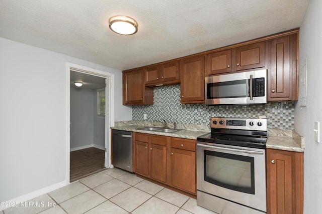 3303 Jones St, Jacksonville, FL 32206 - kitchen with appliances with stainless steel finishes, tasteful backsplash, brown cabinets, and light tile patterned flooring