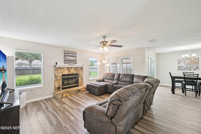 96016 Gray Heron Ct, Yulee, FL 32097 - living room with wood finished floors, a chandelier, ceiling fan, a textured ceiling, and a stone fireplace