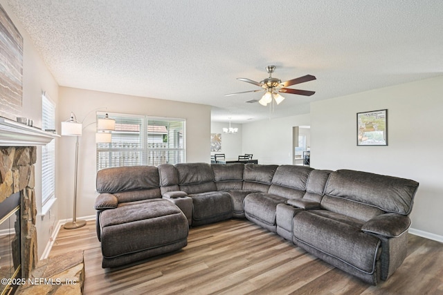 96016 Gray Heron Ct, Yulee, FL 32097 - living area with wood finished floors, a ceiling fan, a textured ceiling, a stone fireplace, and a chandelier