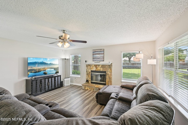 96016 Gray Heron Ct, Yulee, FL 32097 - living area featuring wood finished floors, a textured ceiling, healthy amount of natural light, ceiling fan, and a stone fireplace