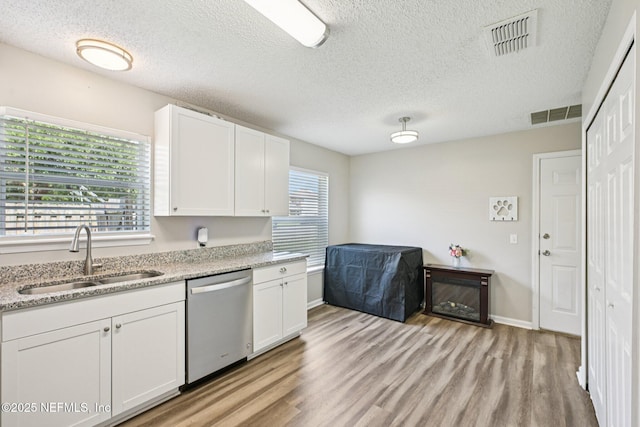96016 Gray Heron Ct, Yulee, FL 32097 - kitchen featuring dishwasher, light wood-type flooring, white cabinets, and a textured ceiling