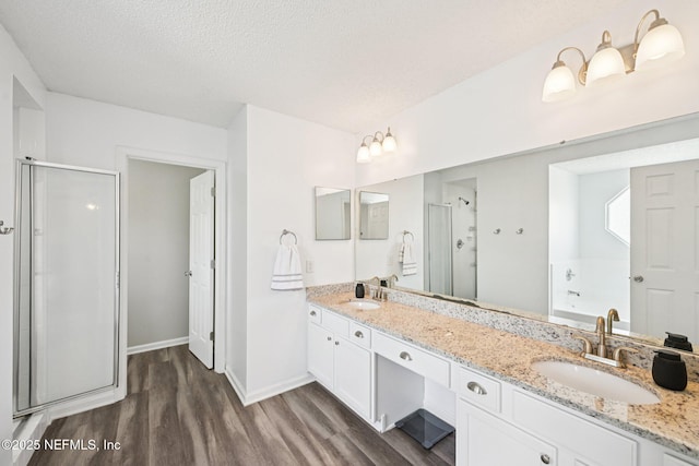 96016 Gray Heron Ct, Yulee, FL 32097 - bathroom with wood finished floors, a shower stall, double vanity, a garden tub, and a textured ceiling