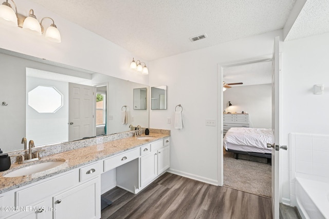 96016 Gray Heron Ct, Yulee, FL 32097 - ensuite bathroom with wood finished floors, double vanity, a tub, a textured ceiling, and ceiling fan
