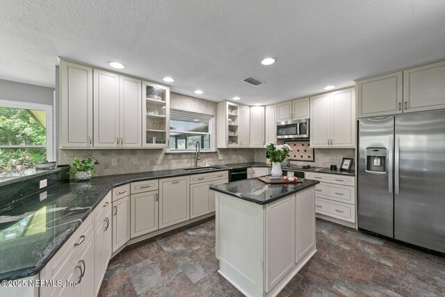 7006 Cypress Bridge Dr N, Ponte Vedra Beach, FL 32082 - kitchen with appliances with stainless steel finishes, dark stone finish flooring, decorative backsplash, glass insert cabinets, and a textured ceiling