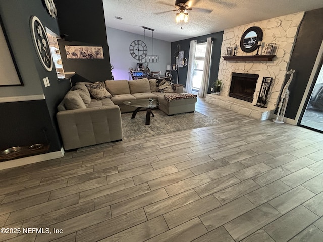 3112 Hampstead Dr, Jacksonville, FL 32225 - living room featuring a ceiling fan, wood finished floors, a textured ceiling, and a stone fireplace