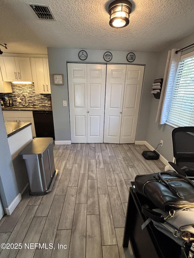3112 Hampstead Dr, Jacksonville, FL 32225 - kitchen with dishwasher, light wood-style floors, dark countertops, a textured ceiling, and white cabinets