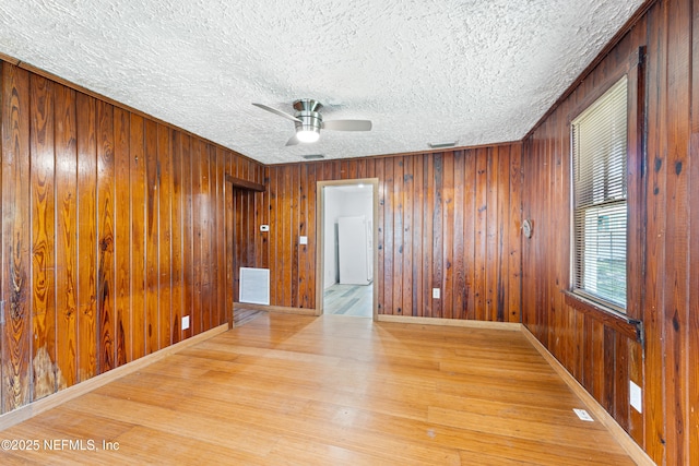 610 Division St, Fernandina Beach, FL 32034 - unfurnished room featuring wood finished floors, a textured ceiling, a ceiling fan, and wood walls