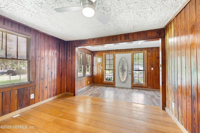 610 Division St, Fernandina Beach, FL 32034 - foyer featuring wood finished floors, wooden walls, a ceiling fan, and a textured ceiling