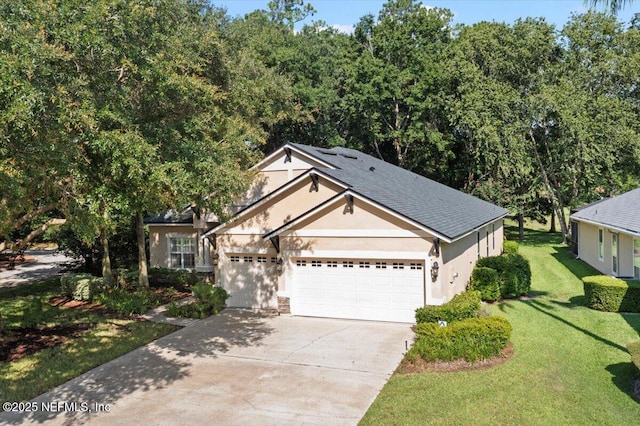 85339 Amagansett Dr, Fernandina Beach, FL 32034 - view of front of property with stucco siding, driveway, a garage, a front lawn, and roof with shingles