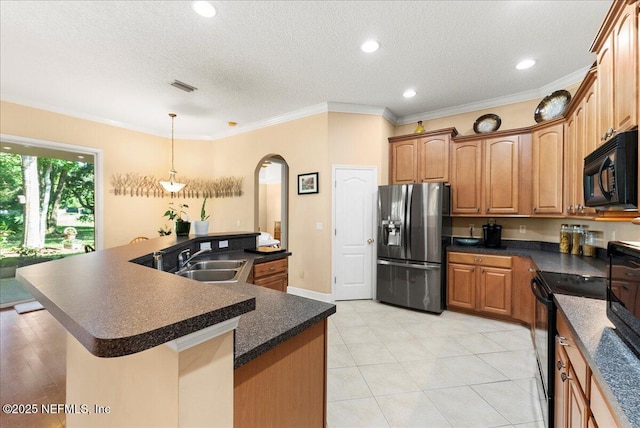 85339 Amagansett Dr, Fernandina Beach, FL 32034 - kitchen featuring black appliances, arched walkways, dark countertops, a textured ceiling, and a large island with sink