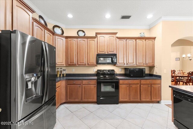 85339 Amagansett Dr, Fernandina Beach, FL 32034 - kitchen featuring black appliances, dark countertops, arched walkways, light tile patterned floors, and ornamental molding
