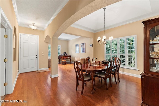 85339 Amagansett Dr, Fernandina Beach, FL 32034 - dining room with arched walkways, wood finished floors, crown molding, and a chandelier