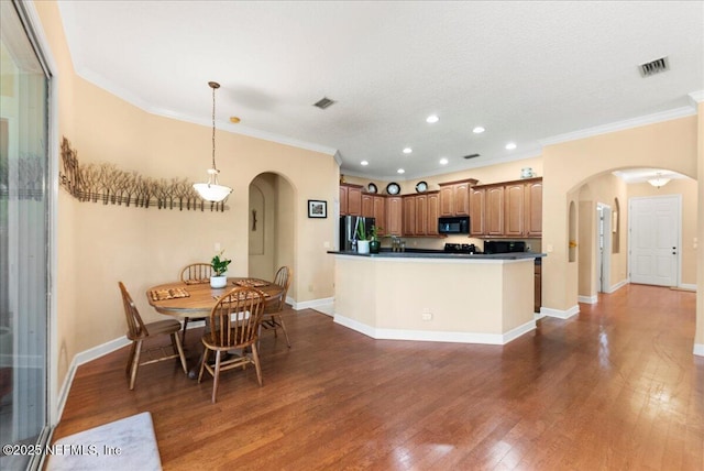 85339 Amagansett Dr, Fernandina Beach, FL 32034 - kitchen with arched walkways, smart refrigerator, black microwave, ornamental molding, and dark wood-type flooring