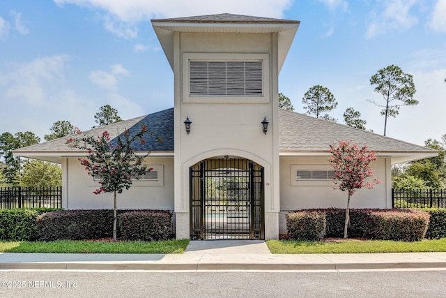 86051 Venetian Ave, Yulee, FL 32097 - view of front of house with a shingled roof, stucco siding, and a gate