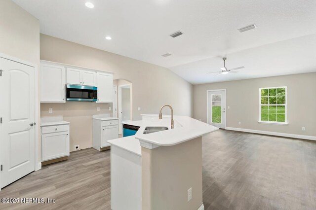 451632 Old Dixie Hwy, Callahan, FL 32011 - kitchen with stainless steel microwave, a ceiling fan, a center island with sink, light wood-type flooring, and white cabinetry
