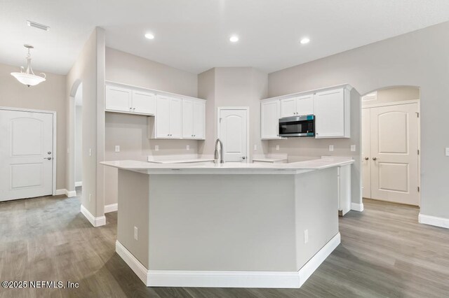 451632 Old Dixie Hwy, Callahan, FL 32011 - kitchen featuring arched walkways, stainless steel microwave, white cabinets, a center island with sink, and recessed lighting