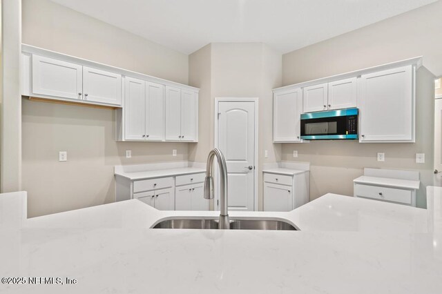 451632 Old Dixie Hwy, Callahan, FL 32011 - kitchen with stainless steel microwave, white cabinetry, and light stone countertops