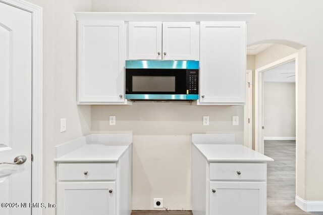 451632 Old Dixie Hwy, Callahan, FL 32011 - kitchen featuring stainless steel microwave, arched walkways, white cabinetry, and light countertops