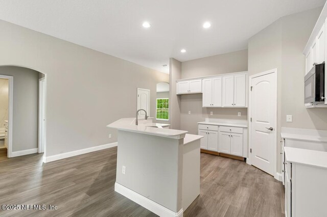 451632 Old Dixie Hwy, Callahan, FL 32011 - kitchen featuring arched walkways, light wood-type flooring, an island with sink, white cabinets, and recessed lighting