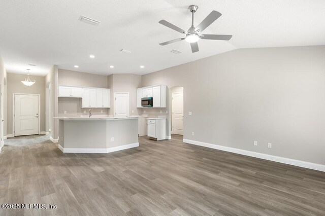 451632 Old Dixie Hwy, Callahan, FL 32011 - kitchen with stainless steel microwave, wood finished floors, open floor plan, light countertops, and white cabinets