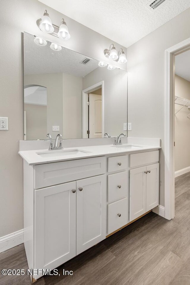 451632 Old Dixie Hwy, Callahan, FL 32011 - full bathroom featuring double vanity, wood finished floors, a walk in closet, and a textured ceiling