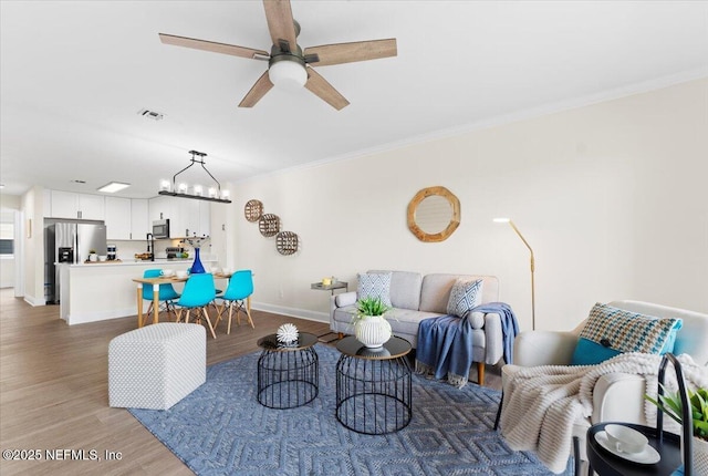 3385 Coastal Hwy Unit 23, Saint Augustine, FL 32084 - living room featuring ornamental molding, a ceiling fan, light wood-type flooring, and a chandelier