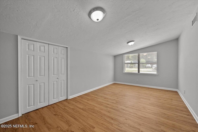 1622 Roselle Ave, Palatka, FL 32177 - unfurnished bedroom with a textured ceiling, light wood finished floors, vaulted ceiling, and a closet