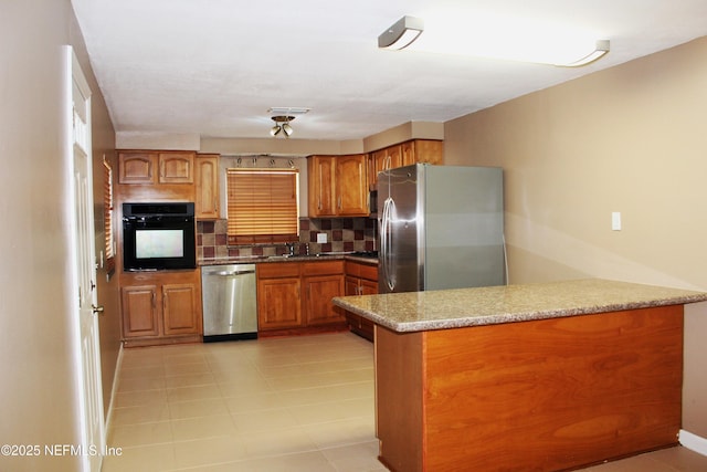 2590 Eastill Dr, Jacksonville, FL 32211 - kitchen with stainless steel appliances, a peninsula, brown cabinetry, and tasteful backsplash