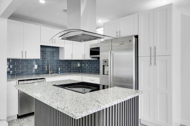 4903 Tennessee St, Jacksonville, FL 32208 - kitchen featuring island exhaust hood, appliances with stainless steel finishes, white cabinets, backsplash, and light stone counters