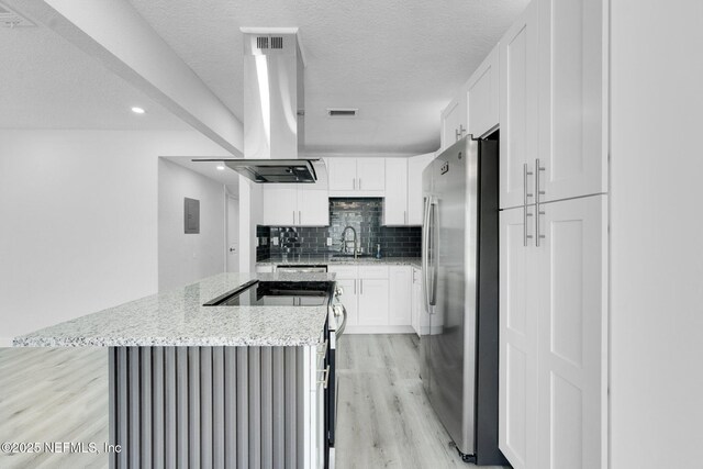 4903 Tennessee St, Jacksonville, FL 32208 - kitchen with stainless steel appliances, a kitchen island, island range hood, light wood finished floors, and decorative backsplash