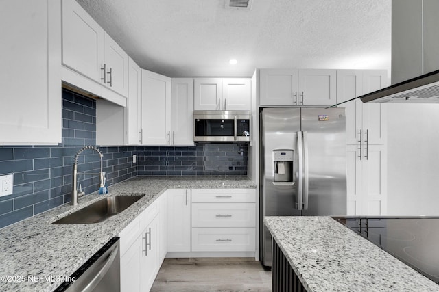 4903 Tennessee St, Jacksonville, FL 32208 - kitchen with stainless steel appliances, a textured ceiling, white cabinetry, light wood-style floors, and light stone counters