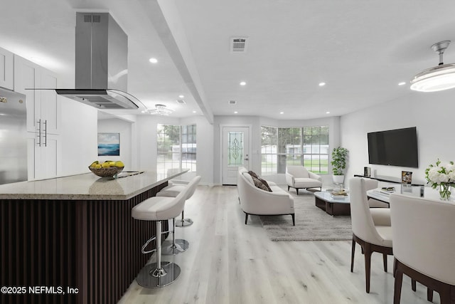 4903 Tennessee St, Jacksonville, FL 32208 - kitchen with island range hood, recessed lighting, light wood-type flooring, a breakfast bar, and light stone countertops