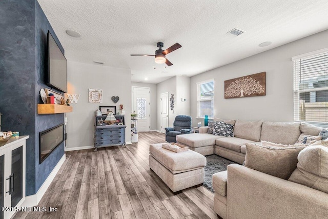 3283 Loblolly Pine Ct, Middleburg, FL 32068 - living area with wood finished floors, a fireplace, ceiling fan, and a textured ceiling