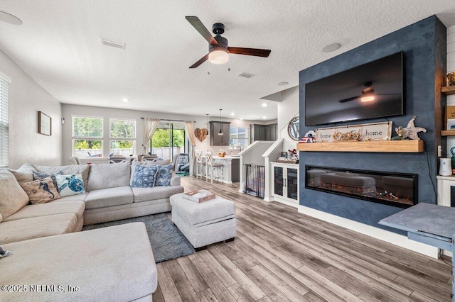 3283 Loblolly Pine Ct, Middleburg, FL 32068 - living area with ceiling fan, wood finished floors, a textured ceiling, a glass covered fireplace, and recessed lighting