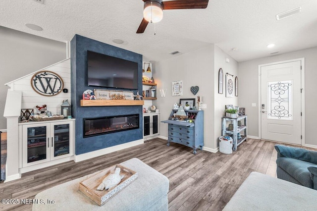 3283 Loblolly Pine Ct, Middleburg, FL 32068 - living room featuring a ceiling fan, a glass covered fireplace, wood finished floors, and a textured ceiling