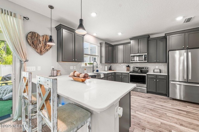 3283 Loblolly Pine Ct, Middleburg, FL 32068 - kitchen with appliances with stainless steel finishes, light countertops, light wood-type flooring, a peninsula, and backsplash