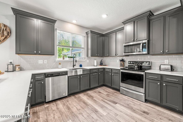 3283 Loblolly Pine Ct, Middleburg, FL 32068 - kitchen with appliances with stainless steel finishes, light wood-style flooring, tasteful backsplash, a textured ceiling, and recessed lighting