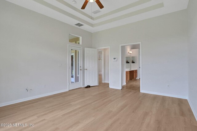 3559 Olympic Dr, Green Cove Springs, FL 32043 - unfurnished bedroom with light wood-style floors, a towering ceiling, a raised ceiling, connected bathroom, and a ceiling fan