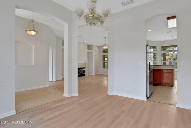 3559 Olympic Dr, Green Cove Springs, FL 32043 - empty room featuring light wood-type flooring, arched walkways, ceiling fan, a glass covered fireplace, and a chandelier