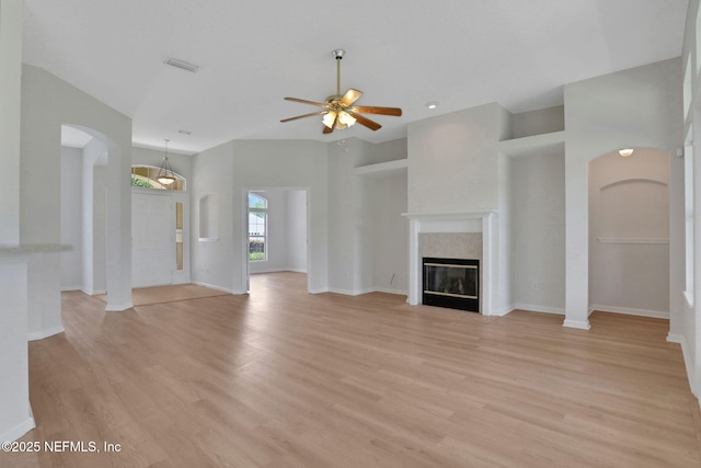 3559 Olympic Dr, Green Cove Springs, FL 32043 - unfurnished living room featuring light wood finished floors, ceiling fan, arched walkways, and a fireplace