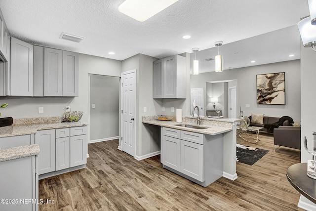 7442 Richardson Rd, Jacksonville, FL 32209 - kitchen with wood finished floors, a peninsula, open floor plan, light stone counters, and a textured ceiling