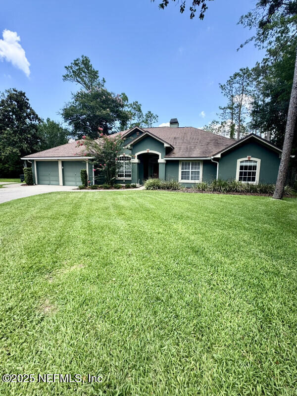 1703 Hunters Ridge Rd, Fleming Island, FL 32003 - ranch-style home with a front yard, driveway, an attached garage, and a chimney