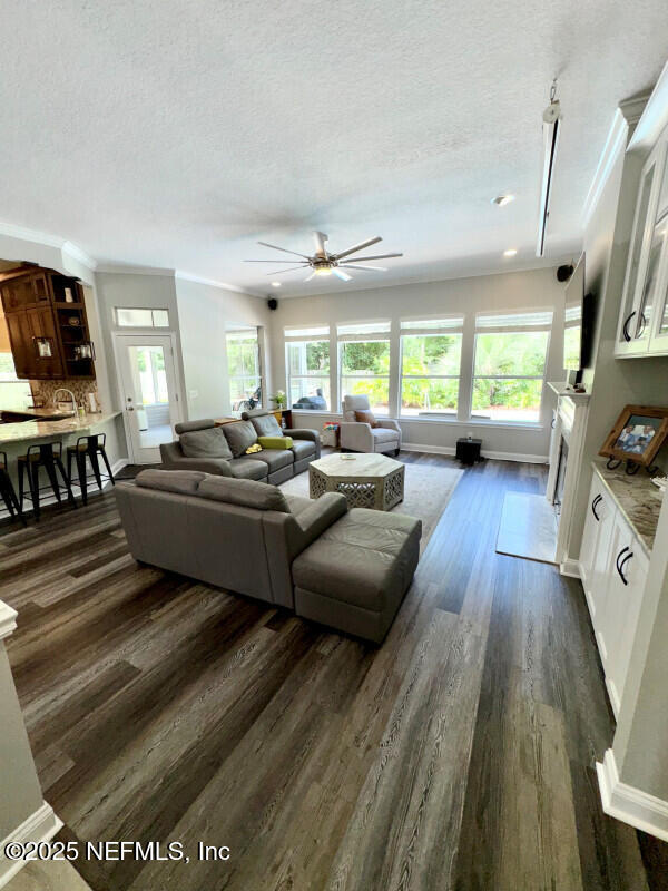 1703 Hunters Ridge Rd, Fleming Island, FL 32003 - living room with dark wood-style flooring, a textured ceiling, ceiling fan, and ornamental molding