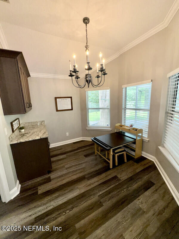 1703 Hunters Ridge Rd, Fleming Island, FL 32003 - dining space with a chandelier, ornamental molding, and dark wood-style floors