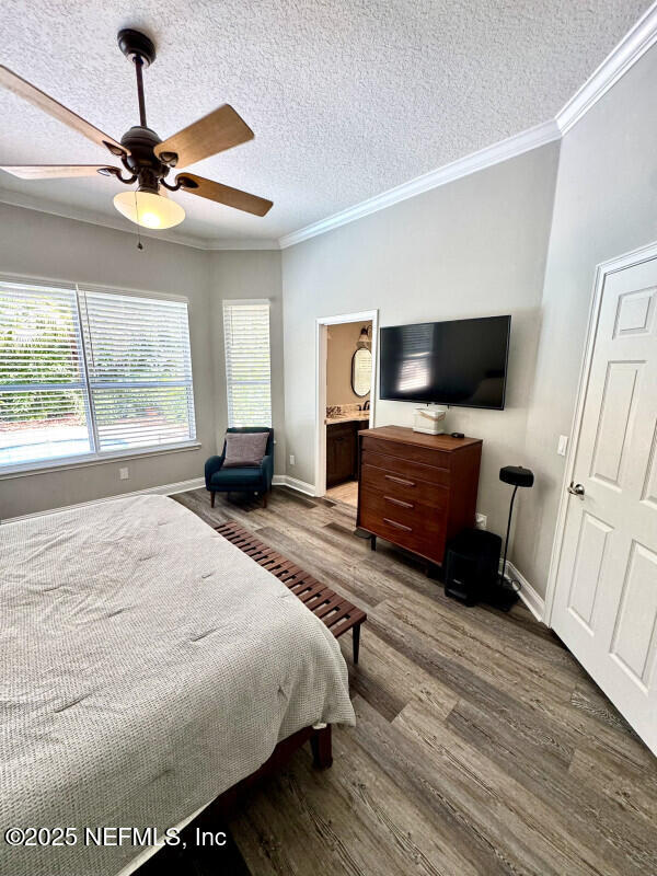 1703 Hunters Ridge Rd, Fleming Island, FL 32003 - bedroom featuring wood finished floors, a textured ceiling, ornamental molding, ceiling fan, and ensuite bath