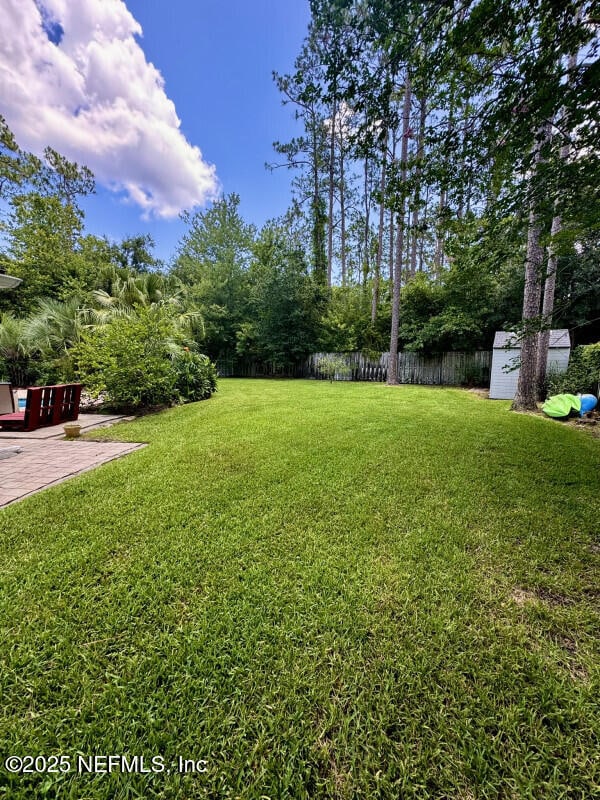 1703 Hunters Ridge Rd, Fleming Island, FL 32003 - fenced backyard featuring a storage unit and a patio area