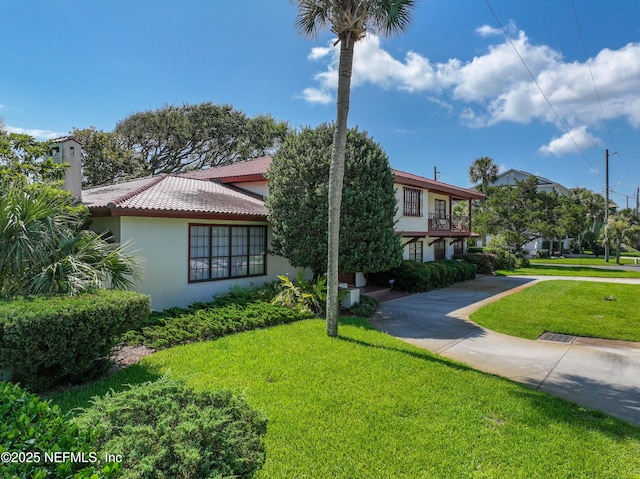 1313 E Coast Dr, Atlantic Beach, FL 32233 - view of front of house with a tiled roof, a front yard, stucco siding, and a chimney