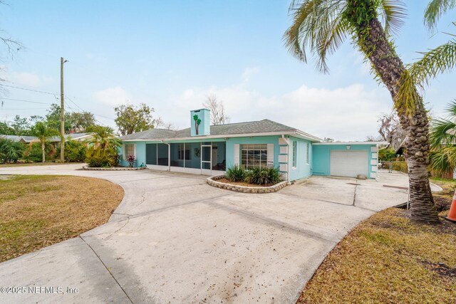 2910 Lake Shore Blvd, Jacksonville, FL 32210 - view of front of house featuring curved driveway, a sunroom, stucco siding, a garage, and a chimney