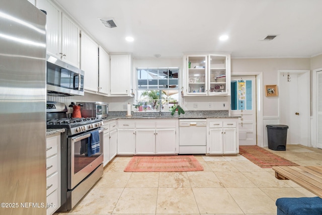 2910 Lake Shore Blvd, Jacksonville, FL 32210 - kitchen featuring stainless steel appliances, light stone countertops, white cabinetry, glass insert cabinets, and crown molding